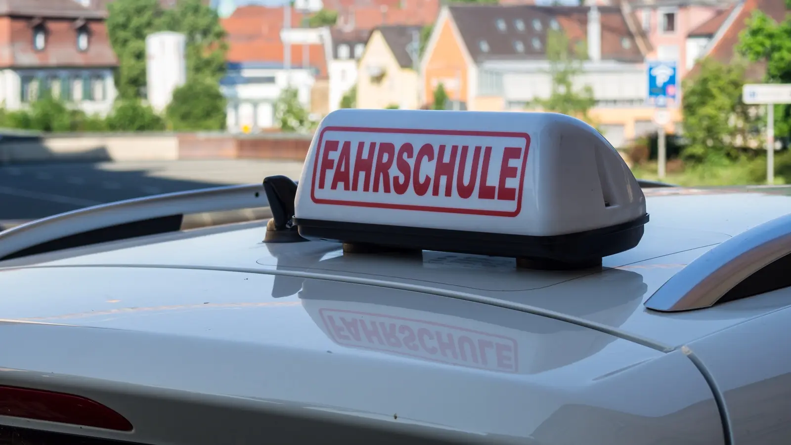 Fahrschulauto mit Fahrschule-Schild auf dem Dach.