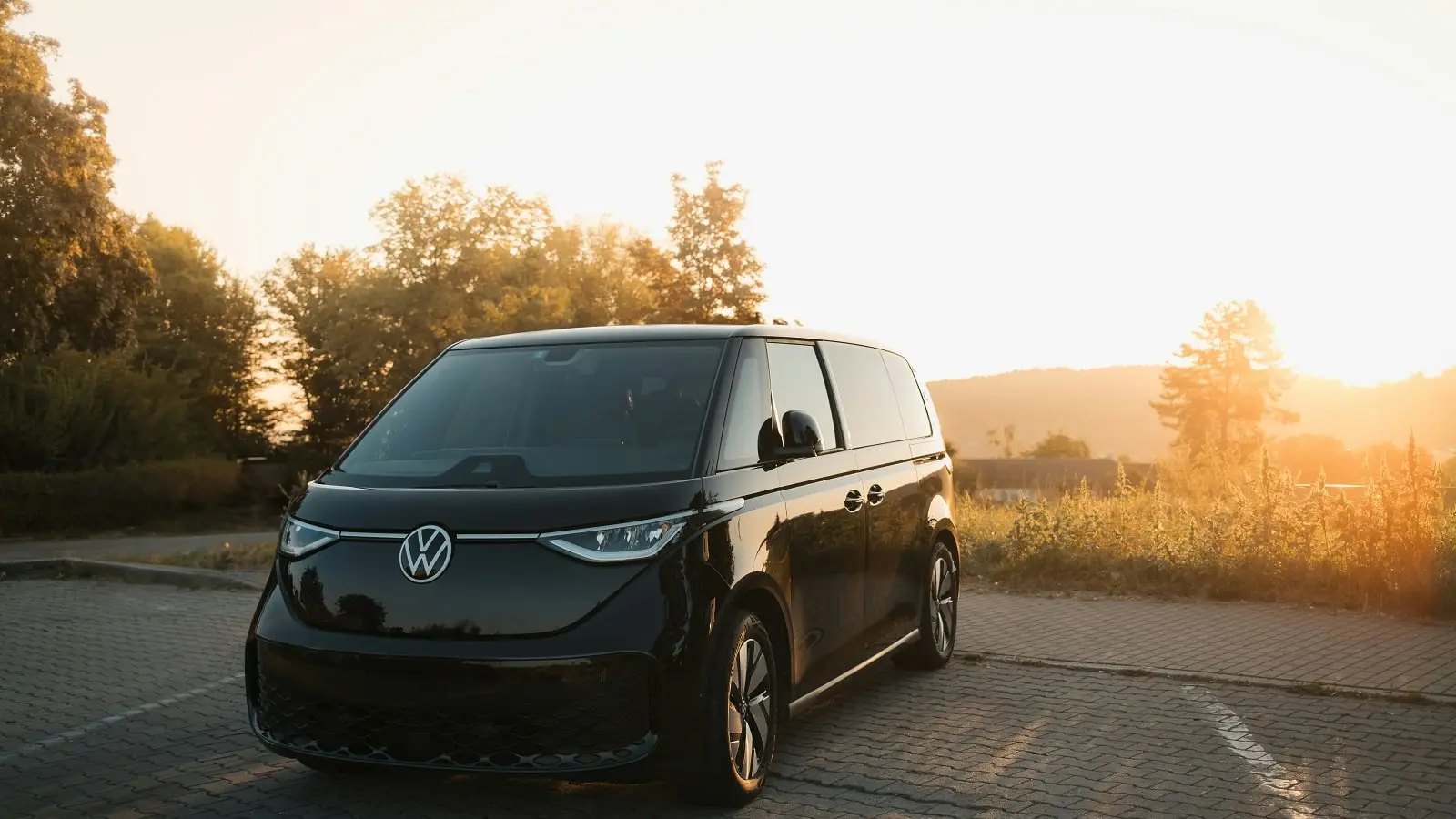 Ein moderner VW T7 steht in der Abendsonne auf einem Parkplatz.